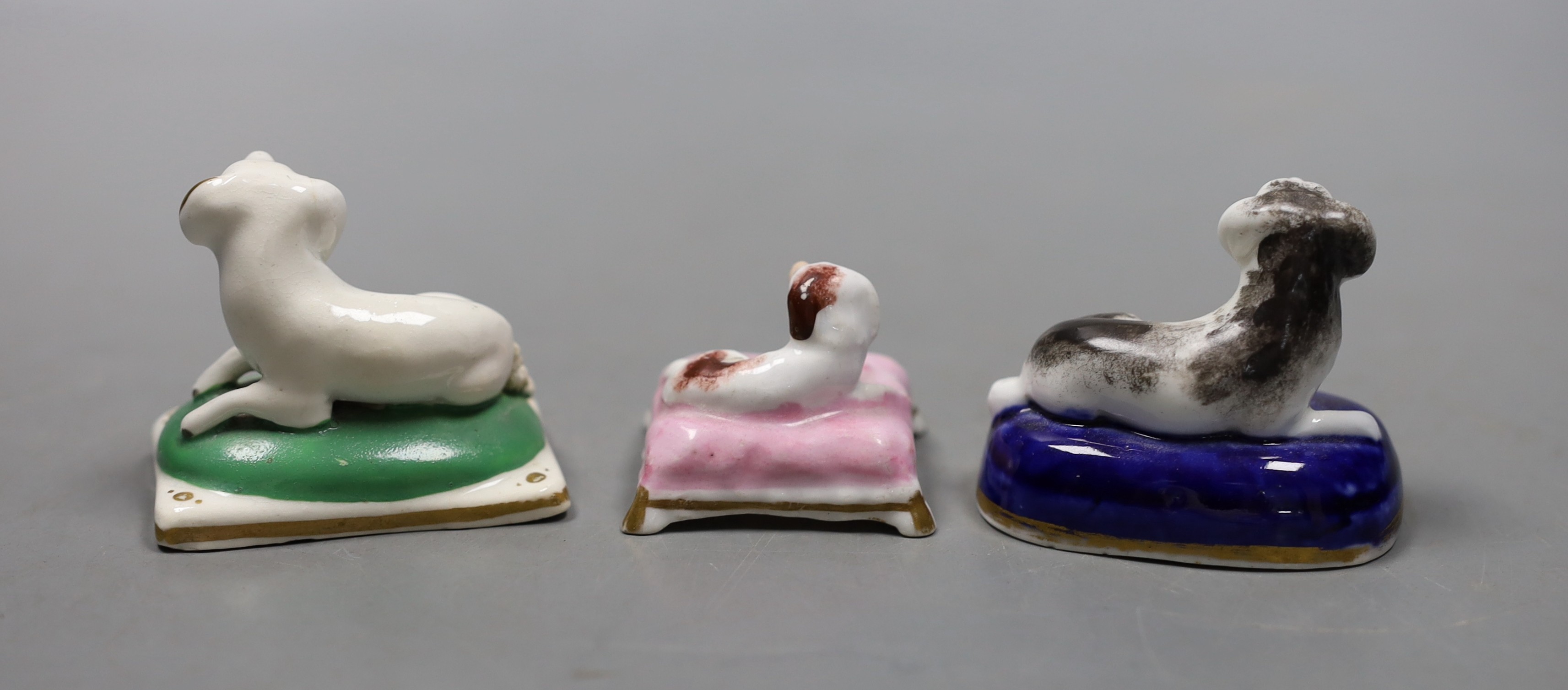 Two English porcelain models of recumbent king Charles spaniels, possibly Davenport, c.1830–50, 5.3cm long and a similar Staffordshire porcelain model on a pink cushion (3), Provenance- Dennis G Rice collection